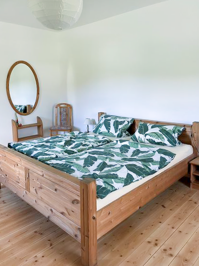 Doppelbett, Stuhl und Spiegel im großen Schlafzimmer